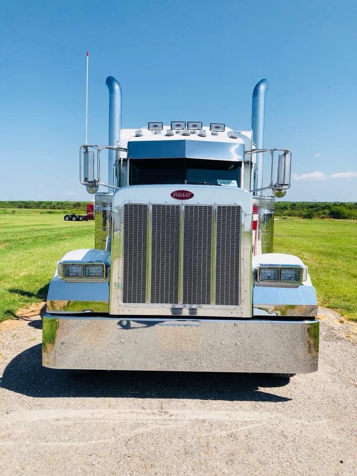A peterbilt semi truck is parked in a grassy field.