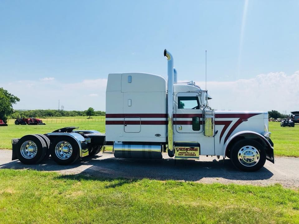 A white semi truck is parked in a grassy field.