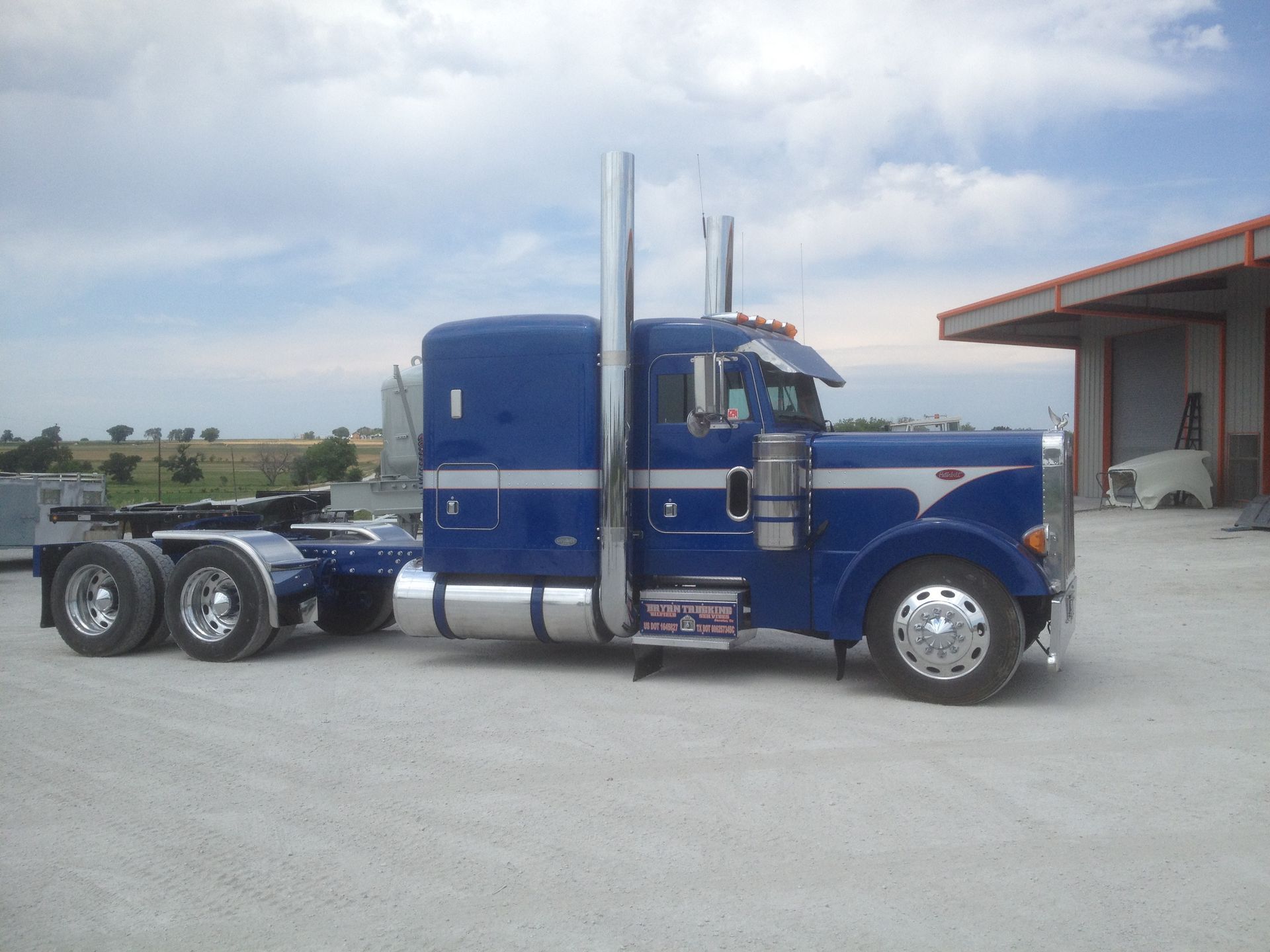 A blue semi truck is parked in front of a building