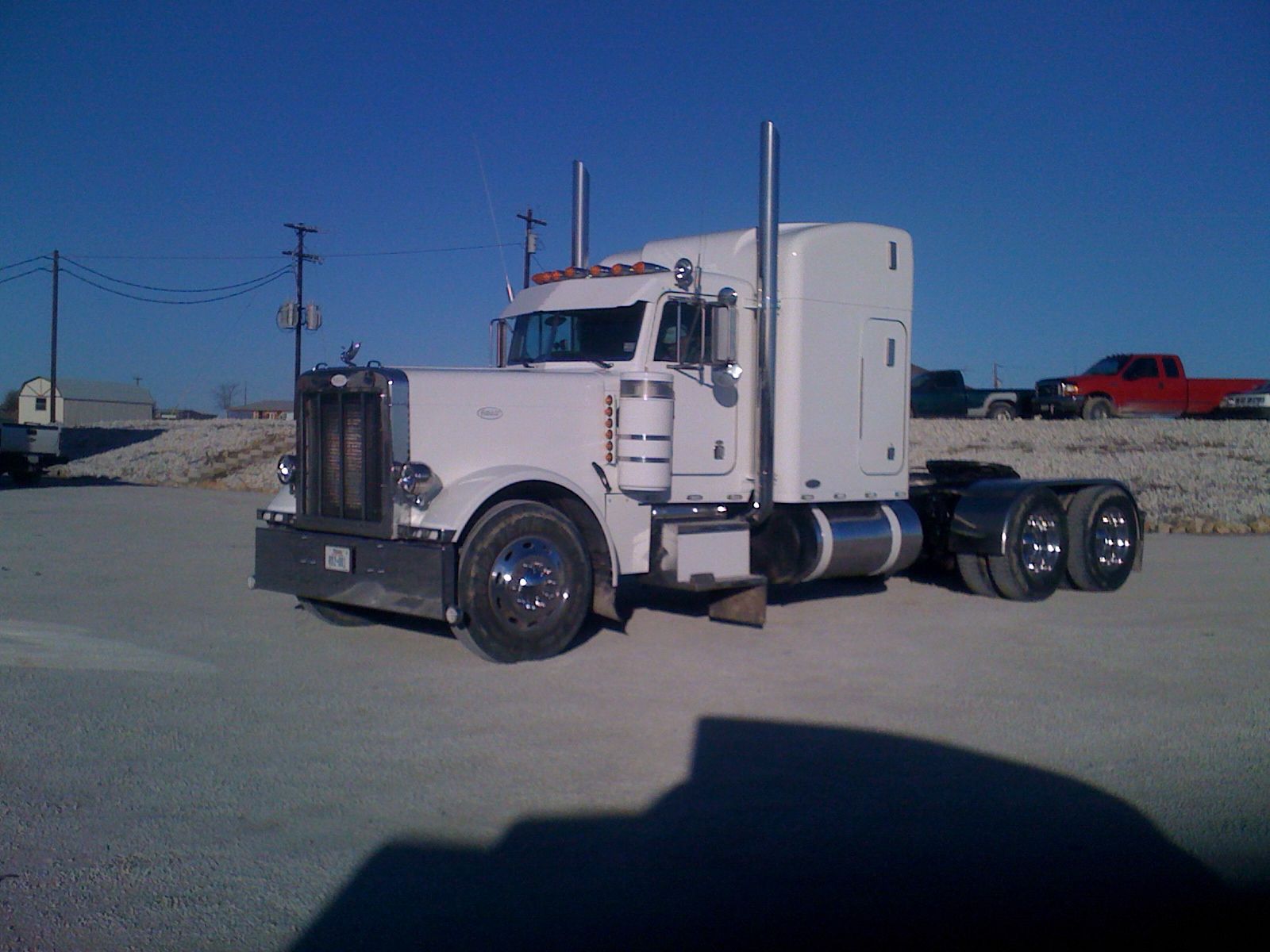A white semi truck is parked on a dirt road