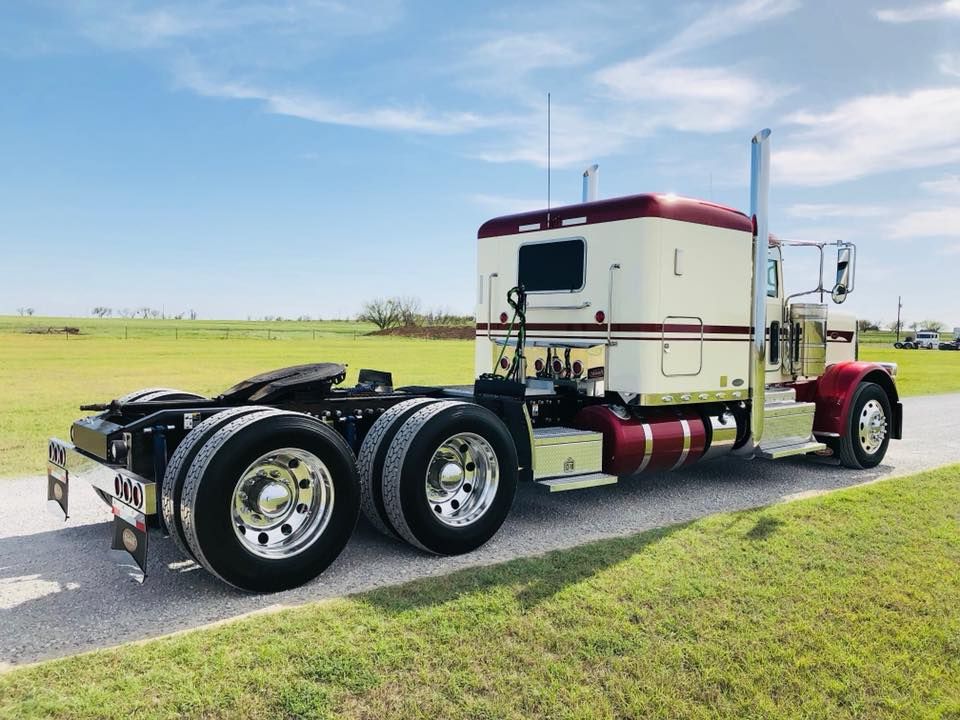 A red and white semi truck is parked on the side of the road.