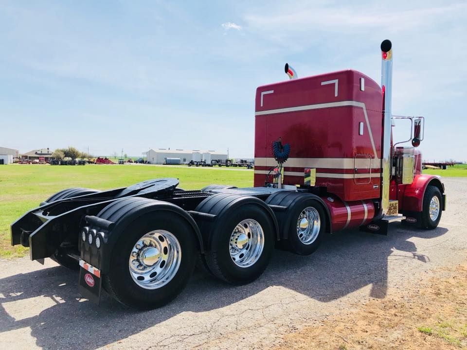 A red semi truck is parked on the side of the road.