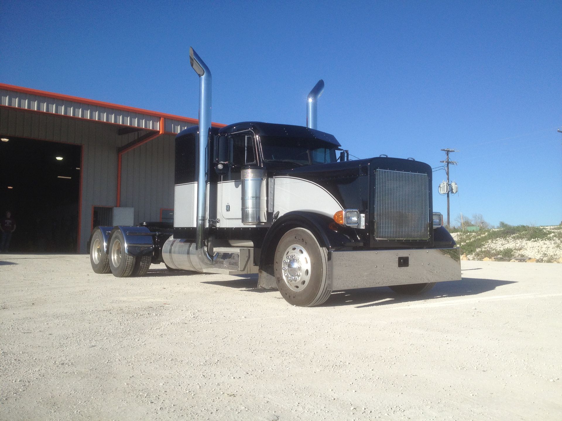A black and white semi truck is parked in front of a building
