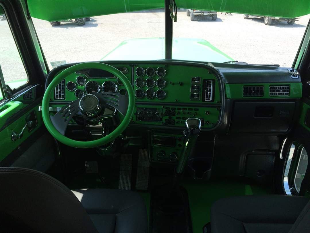 The interior of a green truck with a green steering wheel.