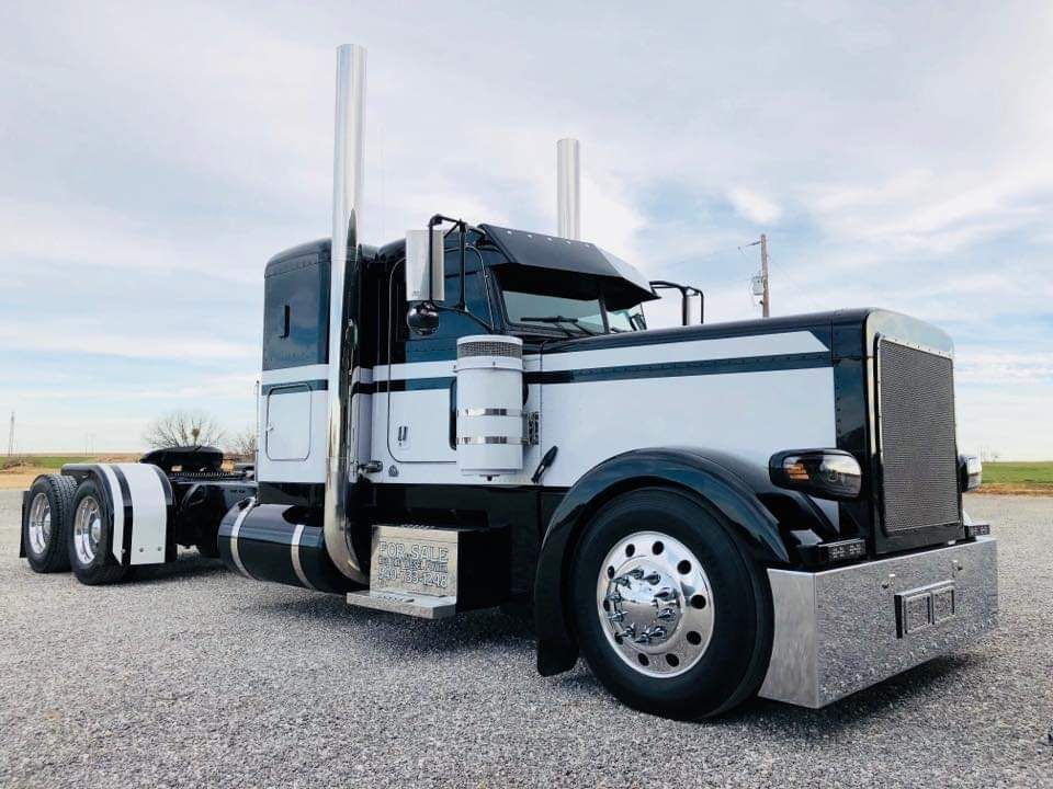 A black and white semi truck is parked in a gravel lot.