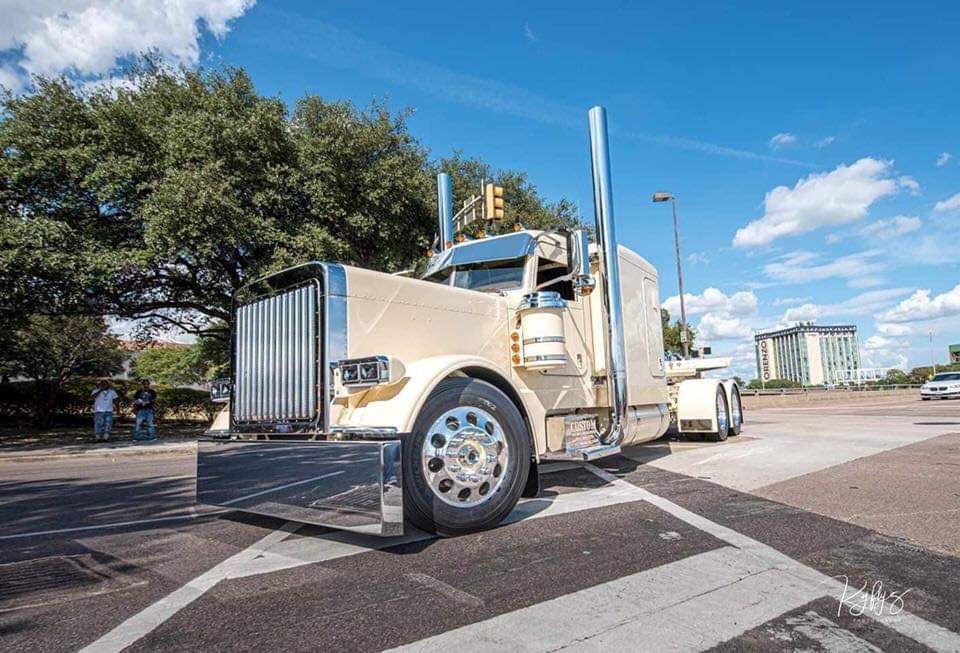 A semi truck is parked on the side of the road in a parking lot.