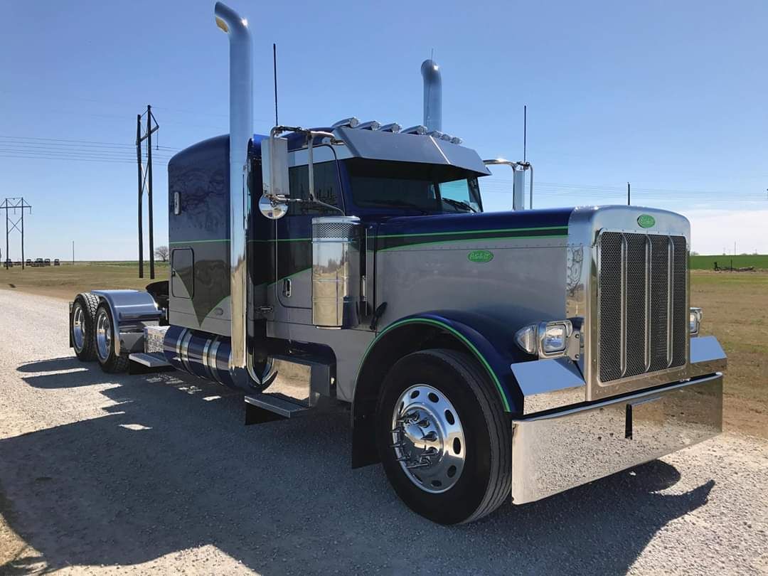 A large semi truck is parked on the side of a dirt road.