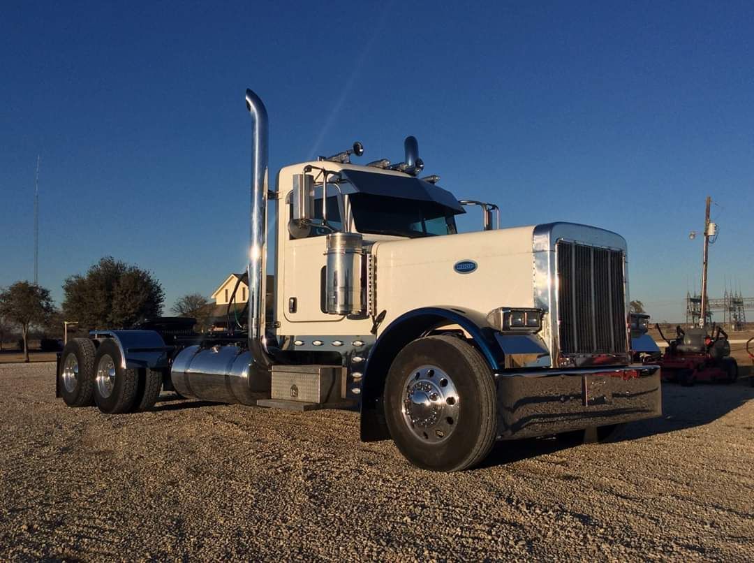 A white semi truck is parked in a gravel lot.