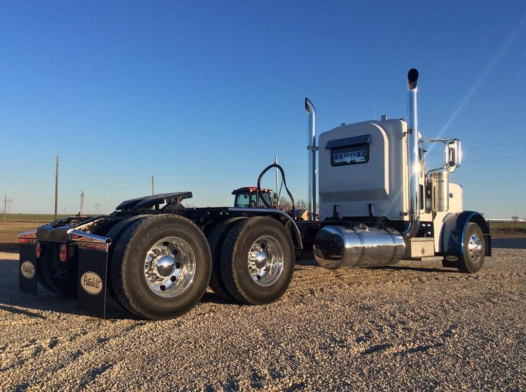 A semi truck is parked on a gravel road.