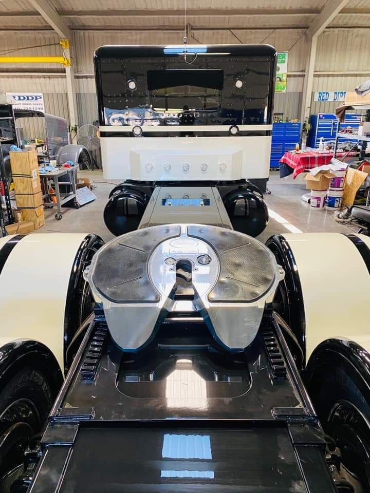 A semi truck is parked in a garage with the hood up.