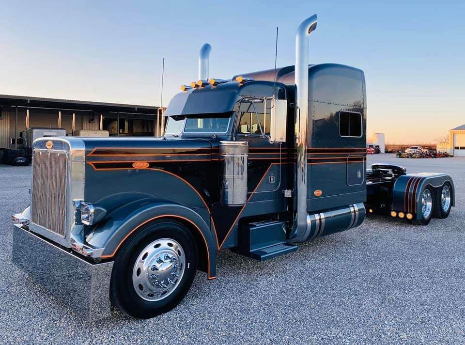 A large semi truck is parked in a gravel lot.