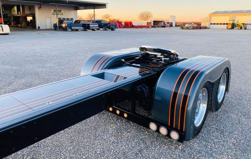 A semi truck with a trailer attached to it is parked in a parking lot.