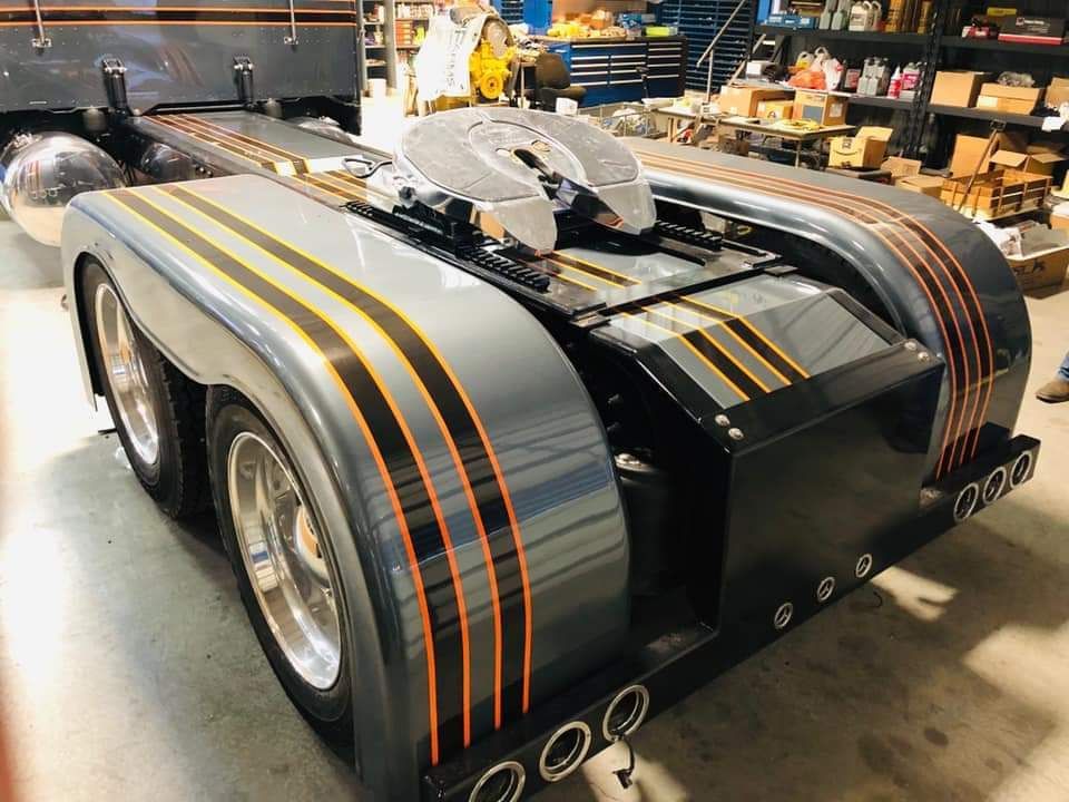 A black truck with orange stripes on the side is parked in a garage.