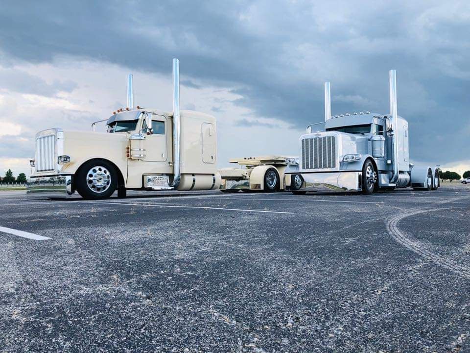 Two semi trucks are parked on the side of the road.