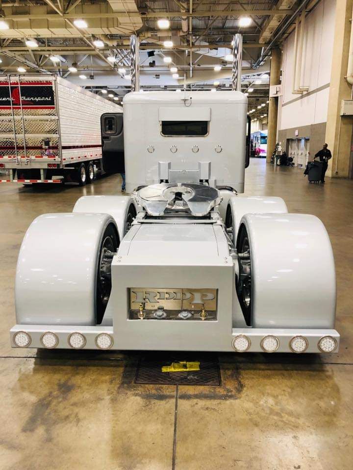 A white semi truck is parked in a warehouse.