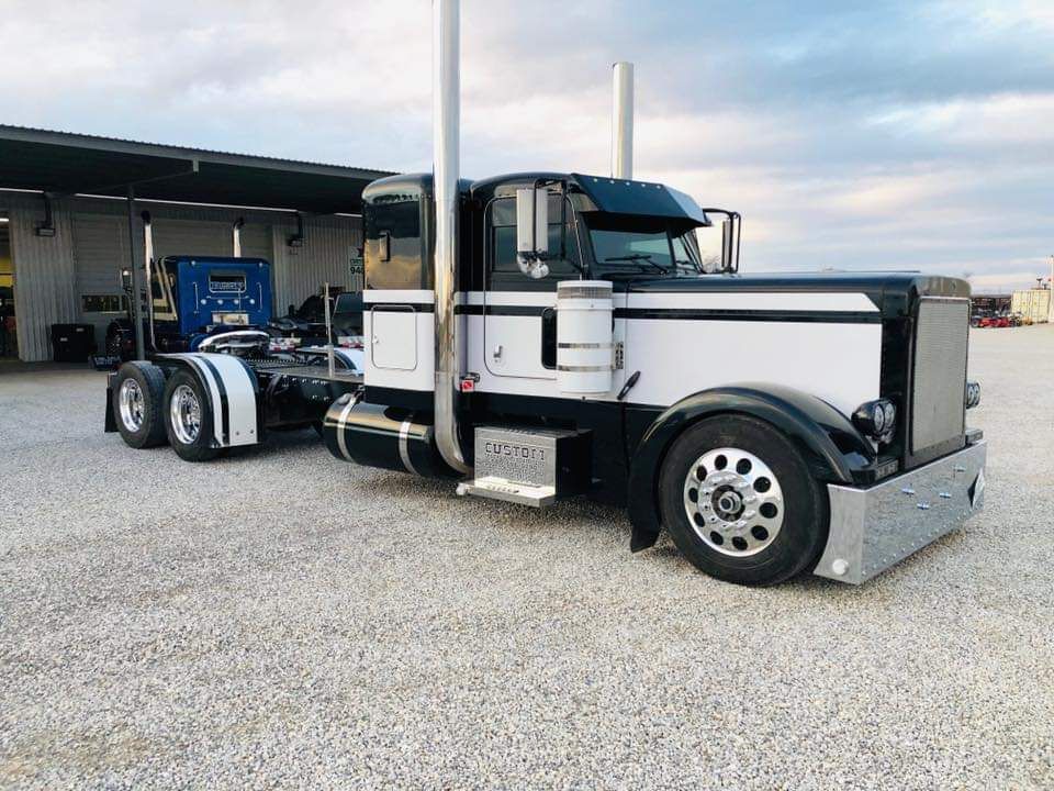 A black and white semi truck is parked in a gravel lot.