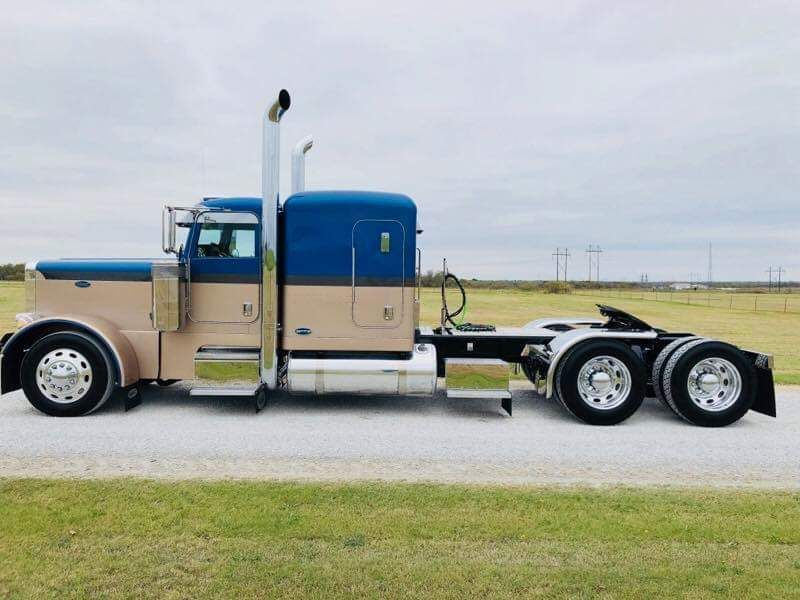 A blue and tan semi truck is parked on the side of the road.