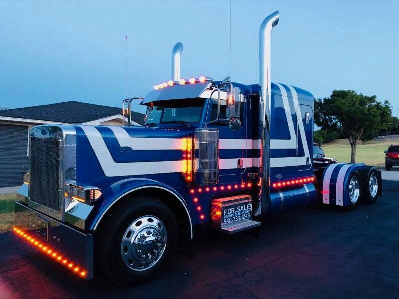 A blue and white semi truck is parked in front of a house