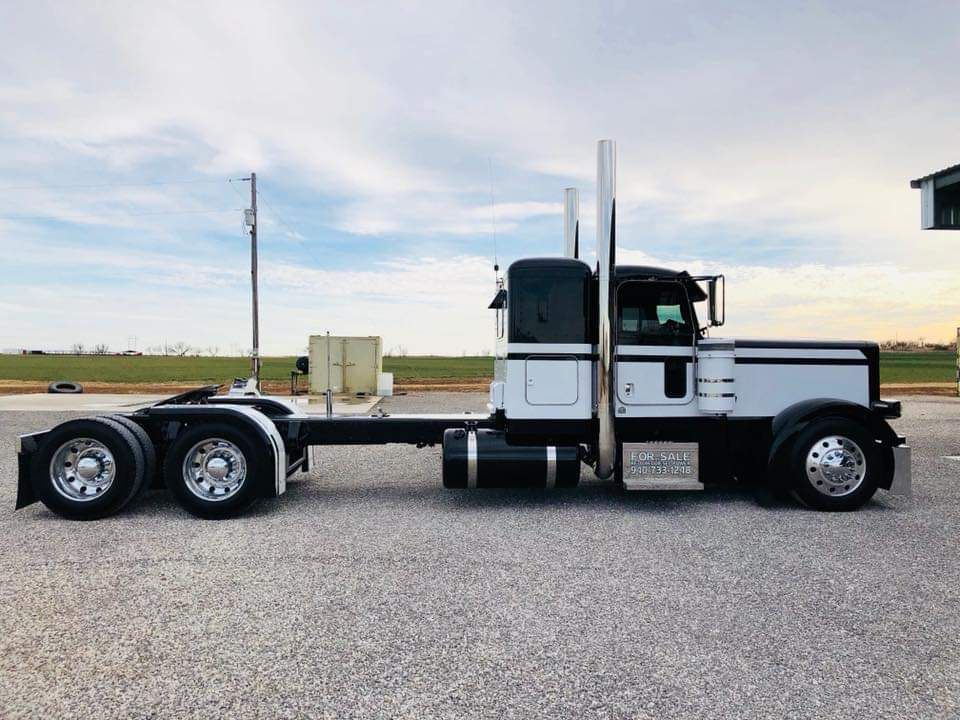 A black and white semi truck is parked on the side of the road.