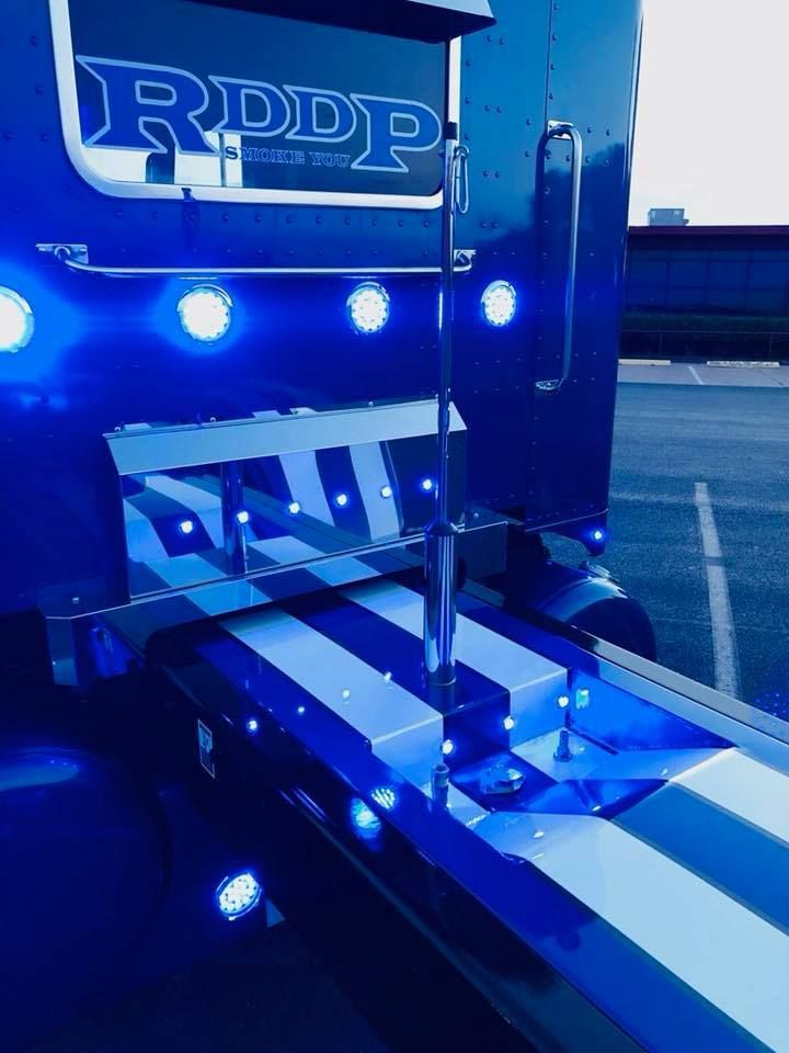 A blue and white semi truck is parked in a parking lot.