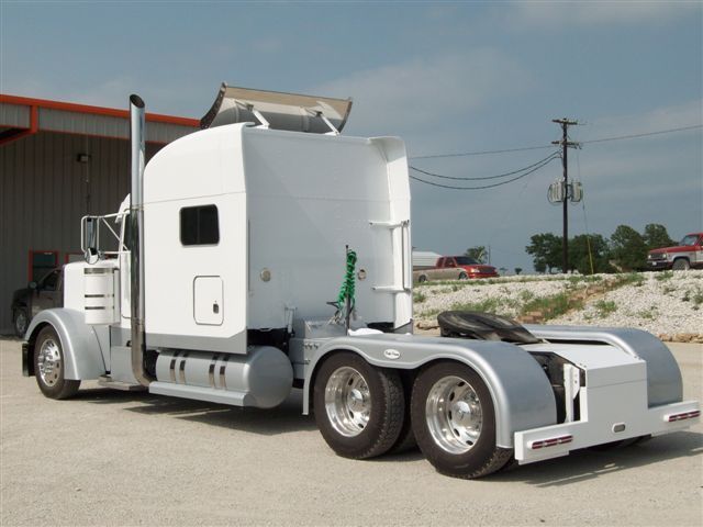 A white semi truck is parked in front of a building