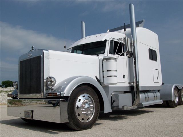A white semi truck is parked on the side of the road