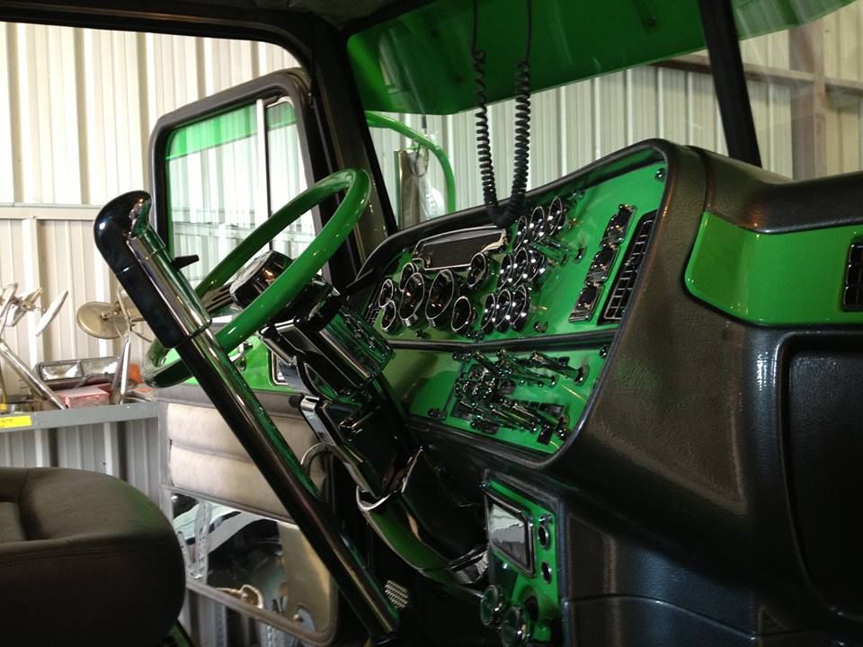 The interior of a green and black truck with a green steering wheel.