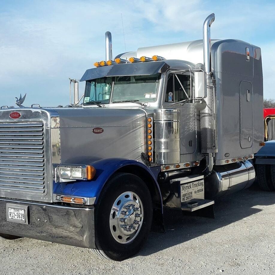 A peterbilt semi truck is parked in a gravel lot