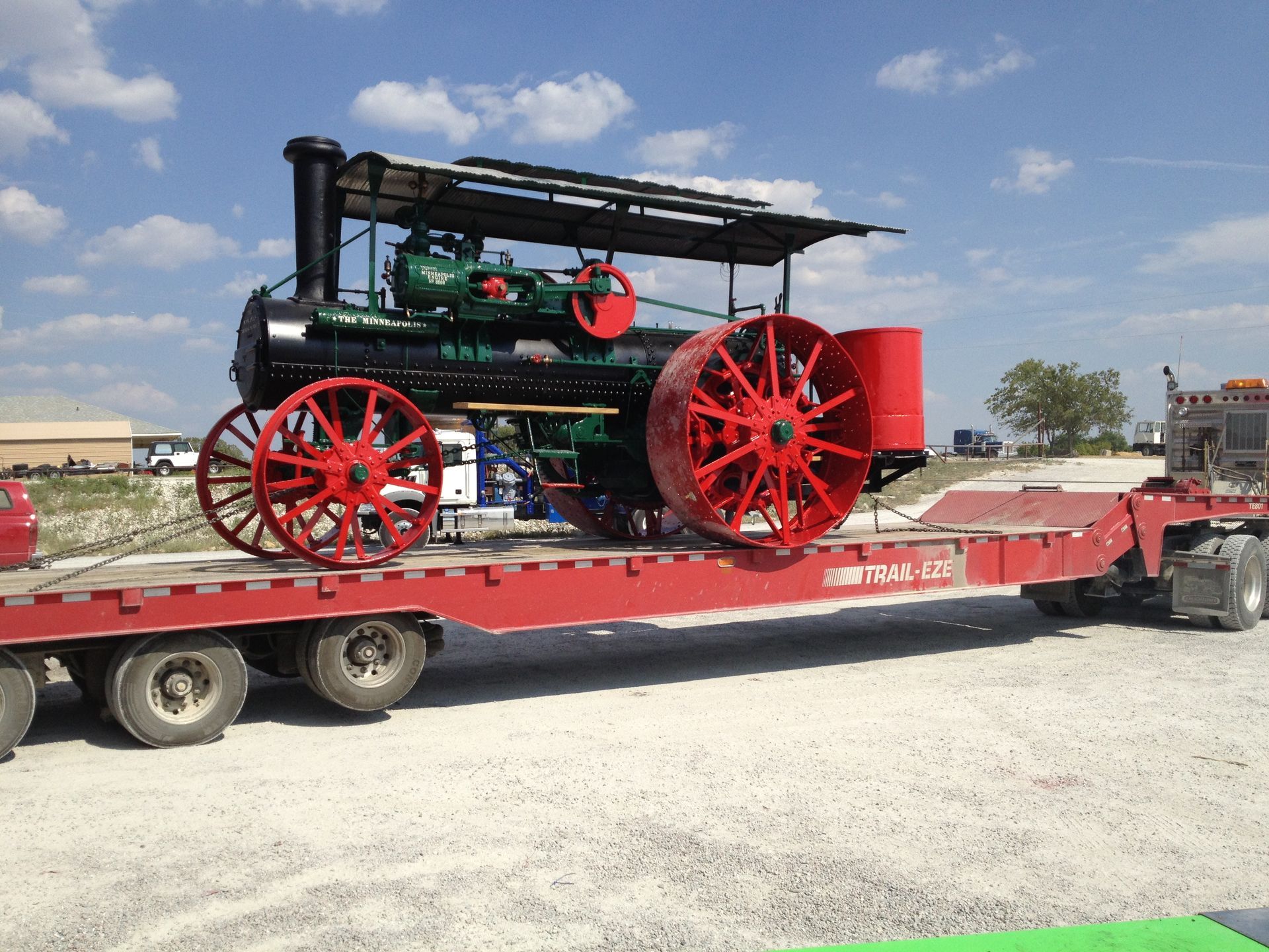 An old steam engine is being transported on a flatbed trailer