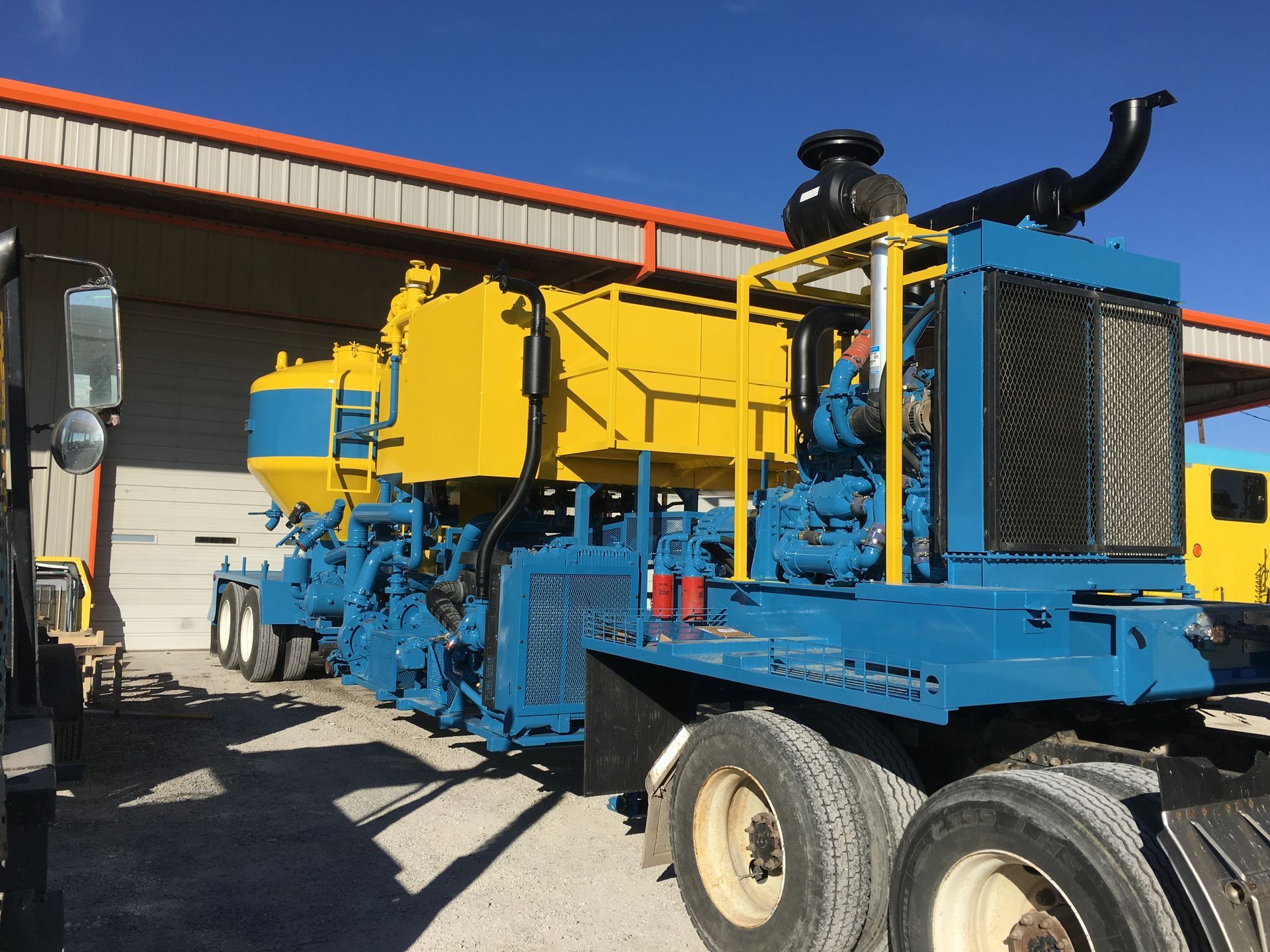 A blue and yellow truck is parked in front of a building