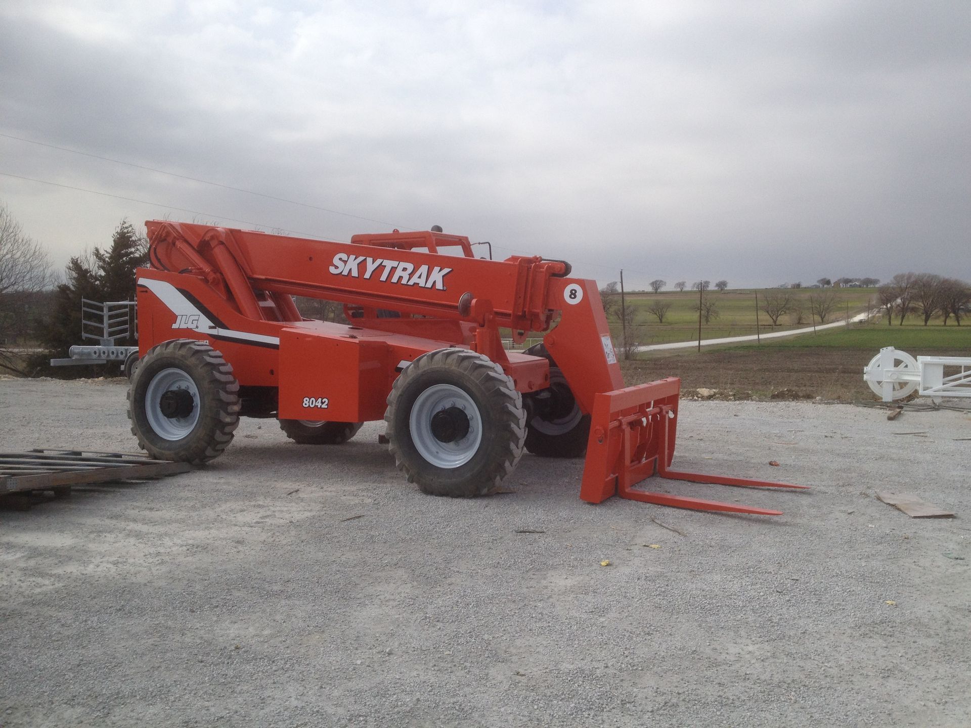 A red skytrax forklift is parked in a gravel lot