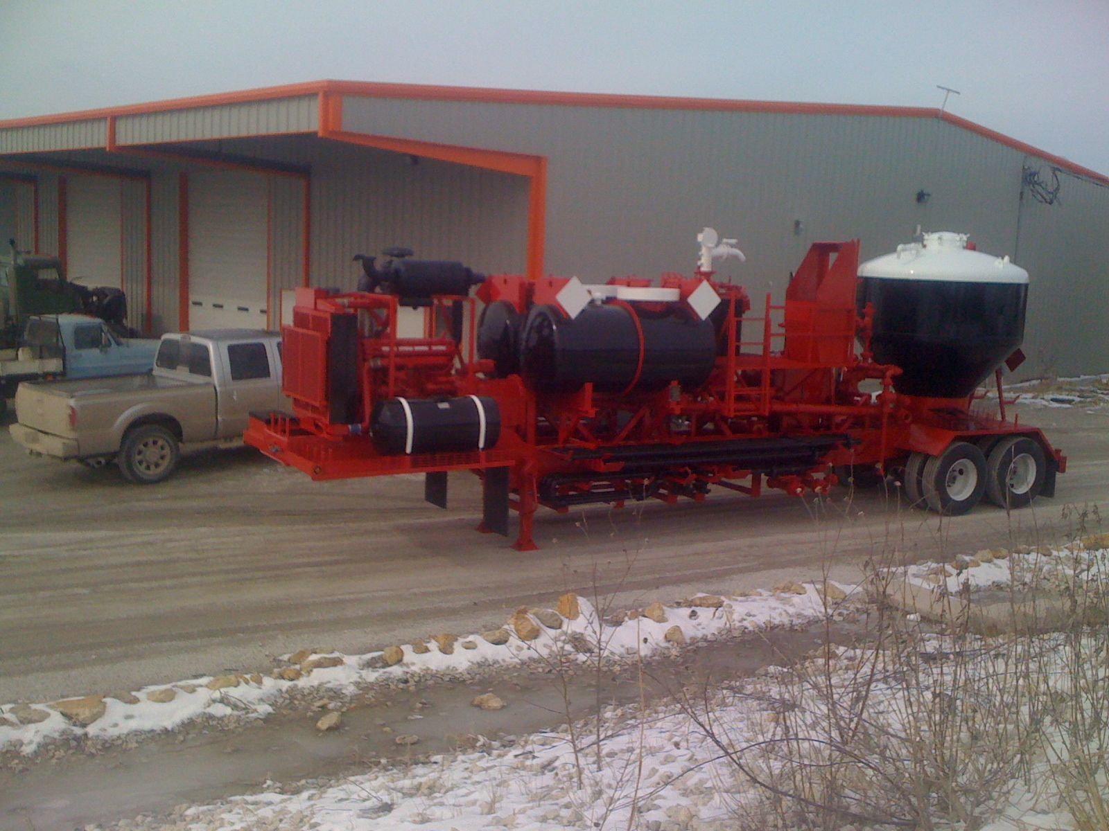 A large red trailer is parked in front of a building.
