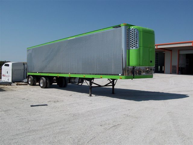A green semi truck is parked in a parking lot