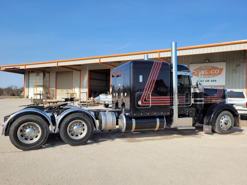 A black semi truck is parked in front of a building.
