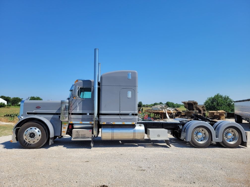 A large semi truck is parked in a gravel lot.
