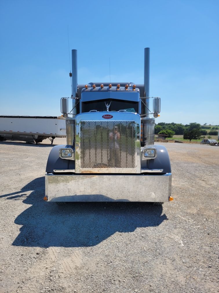A large semi truck is parked in a gravel lot.
