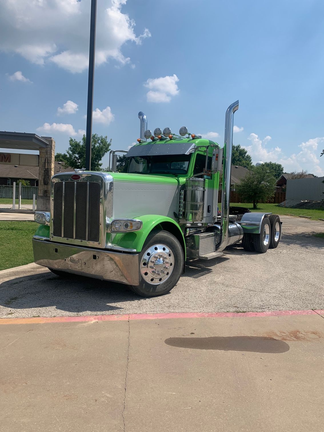 A green semi truck is parked on the side of the road.