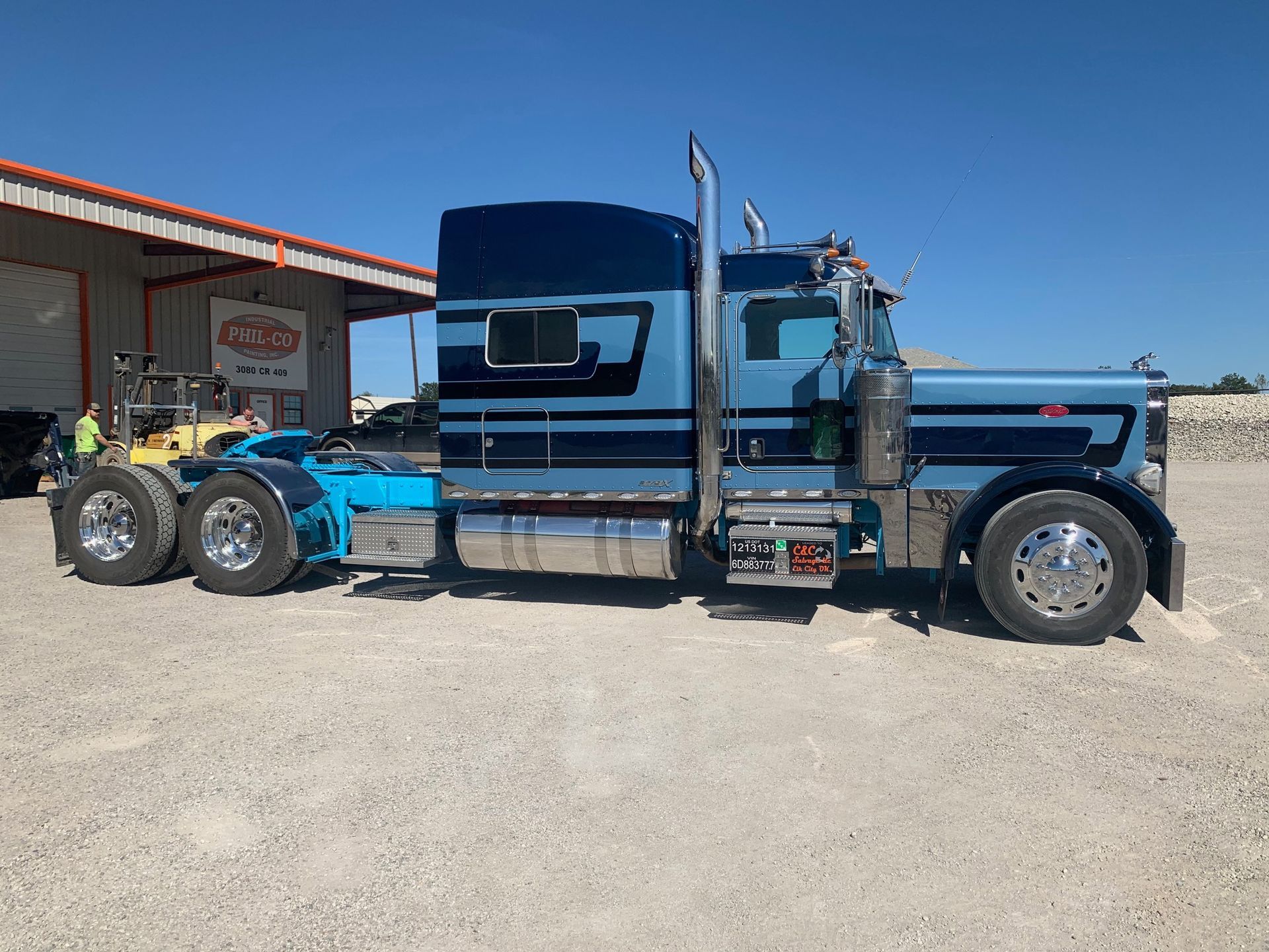 A blue semi truck is parked in front of a building.