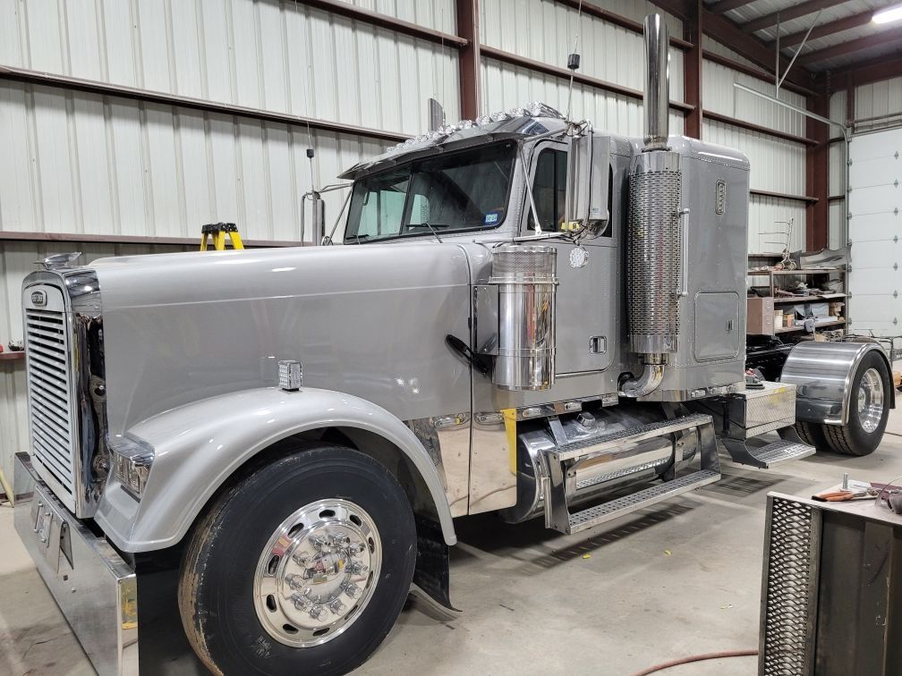 A large gray semi truck is parked in a garage.