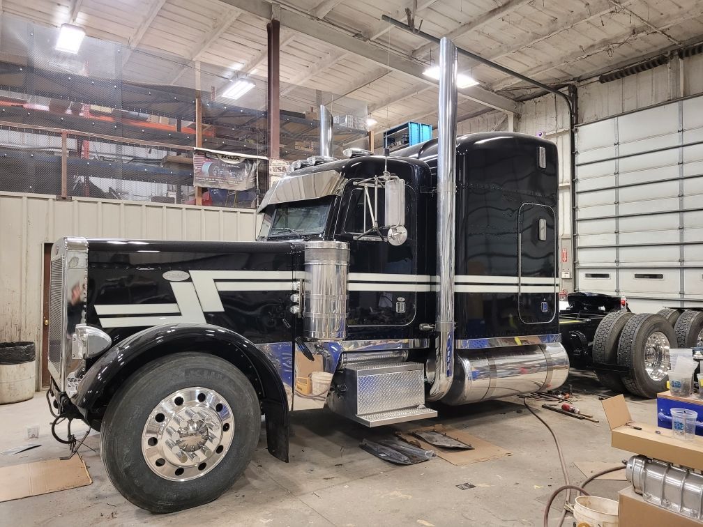 A black semi truck is parked in a garage.