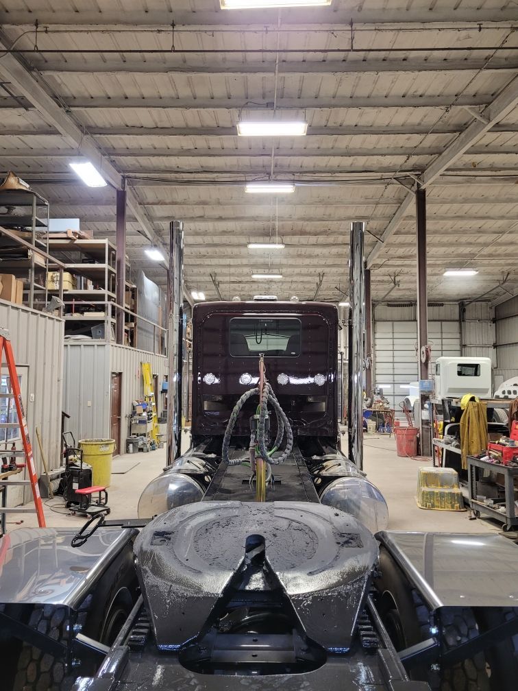 A truck is sitting in a warehouse with a trailer attached to it.