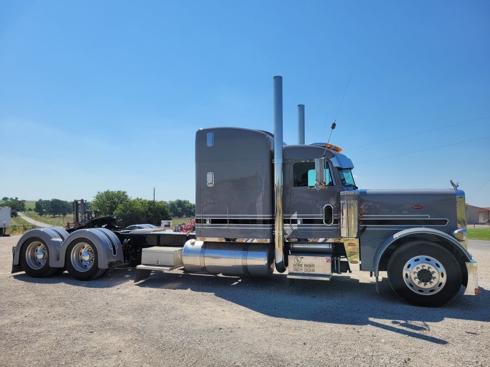 A large gray semi truck is parked in a gravel lot.