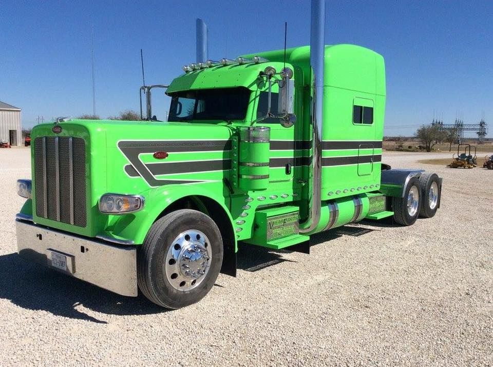 A green semi truck is parked in a gravel lot.
