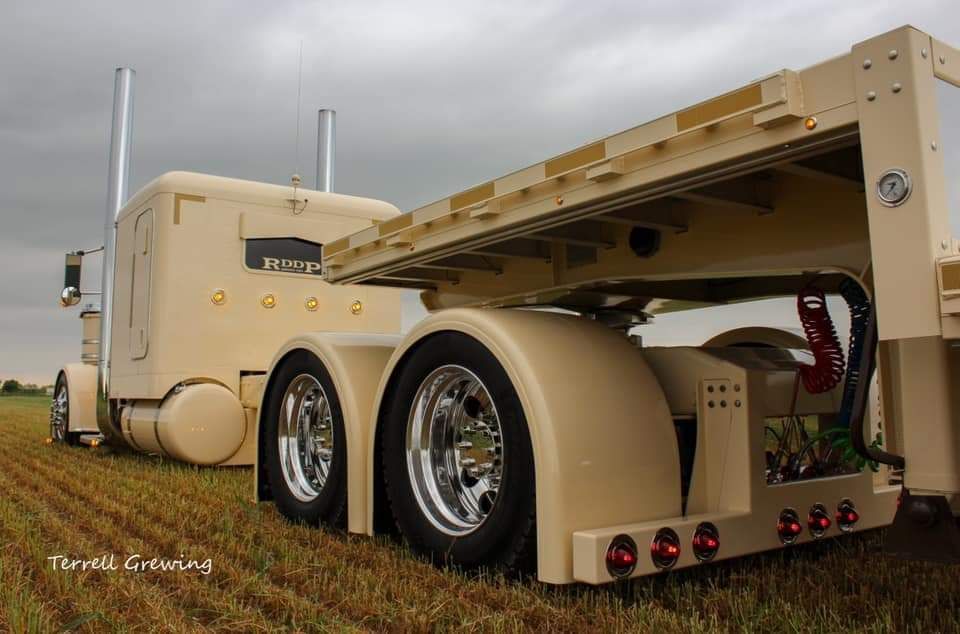 A large semi truck is parked in a grassy field.