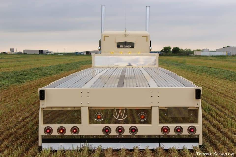 The back of a semi truck is parked in a field.