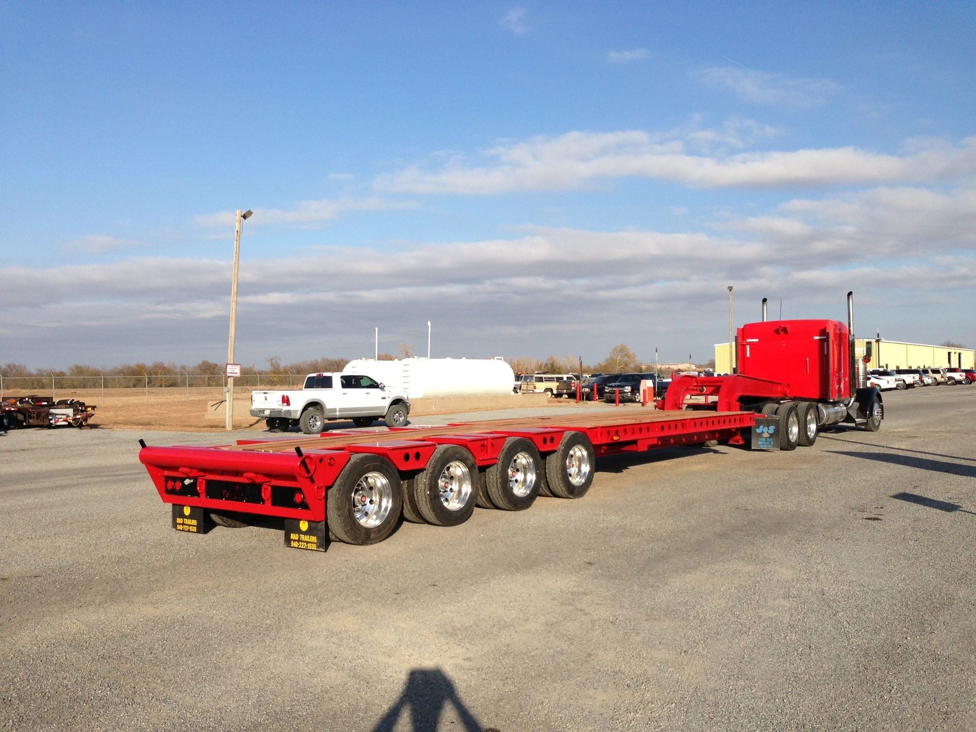 A red semi truck is parked in a parking lot.