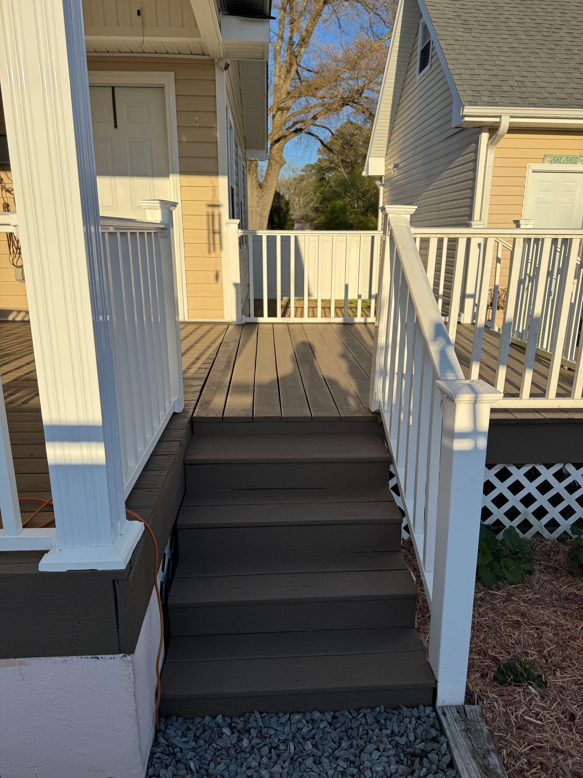 Wooden steps leading up to a deck with white railings and a white porch