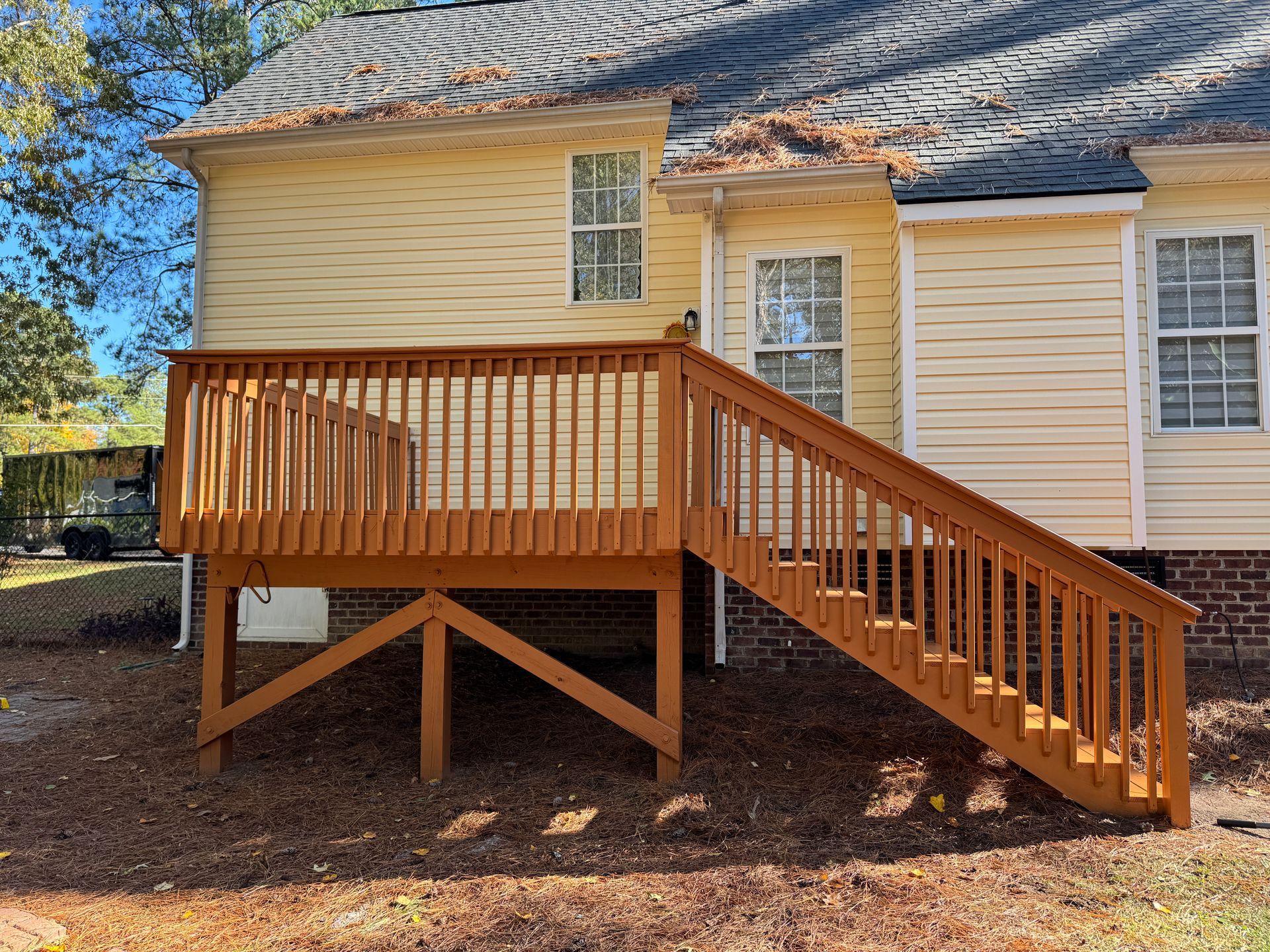 Brown wooden deck with stairs attached to a light yellow house