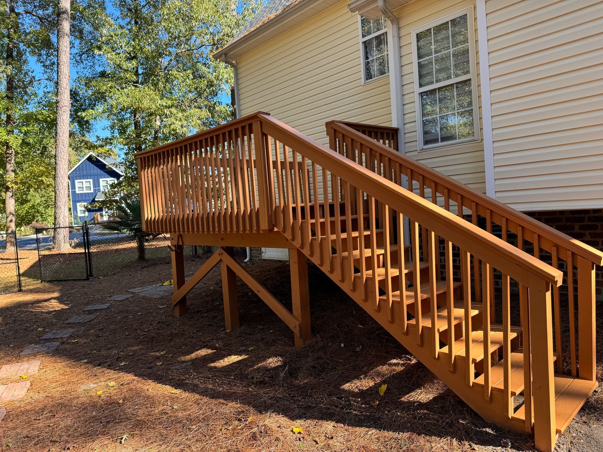 Wooden deck with stairs leading to a light yellow house
