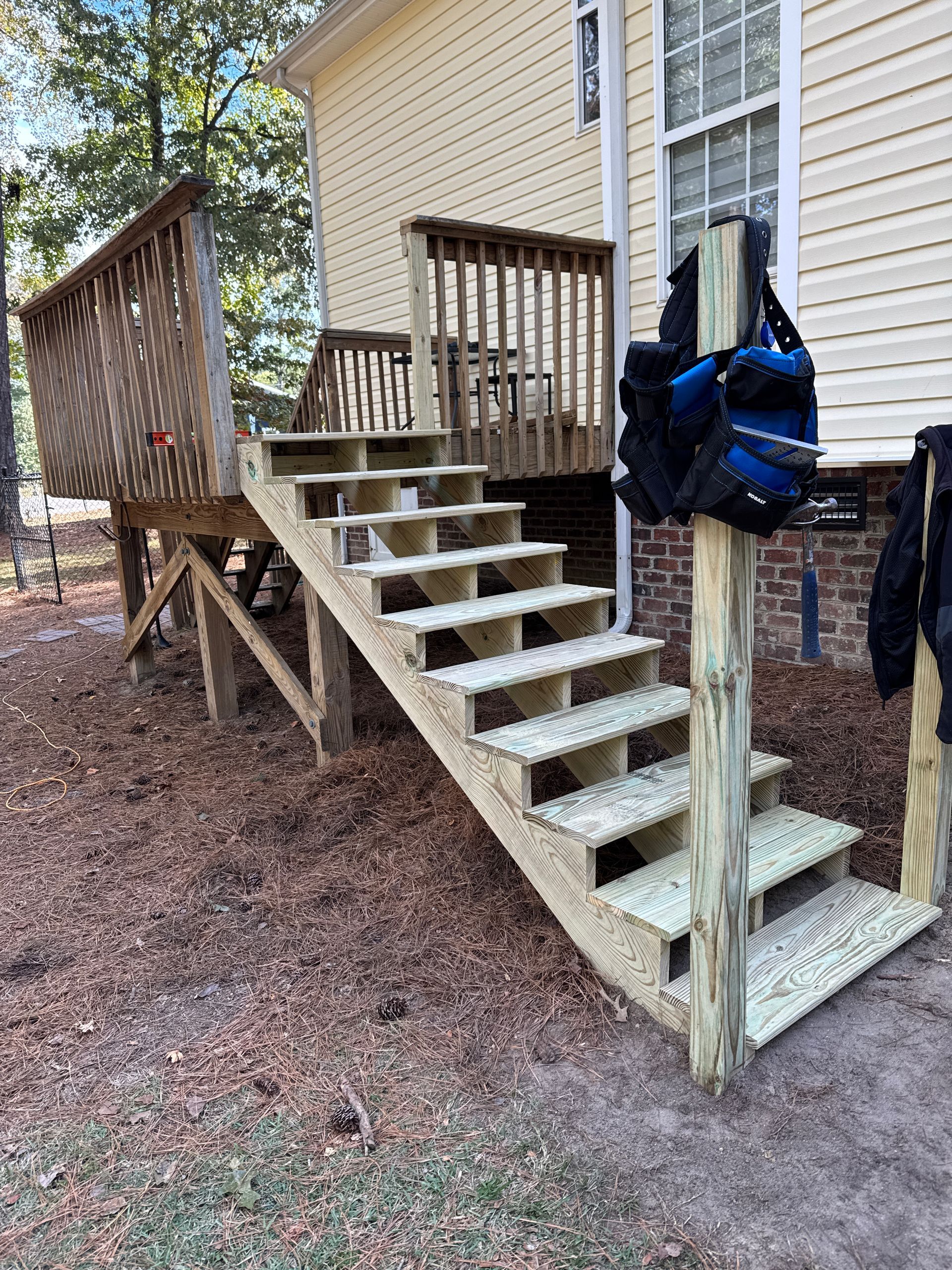 Wooden outdoor stairs leading up to a deck attached to a light yellow house